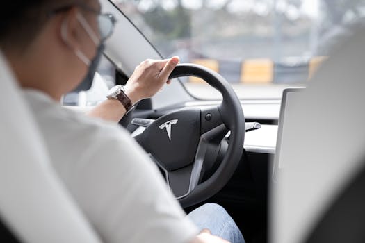 pexels-photo-10029876-10029876 Close-up photo of a person driving a Tesla, showcasing modern vehicle interior design.